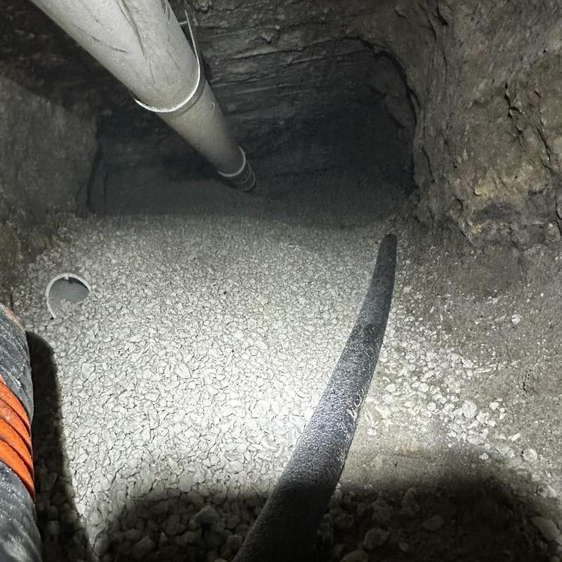 Cast iron pipe backfilled with rock in crawl space