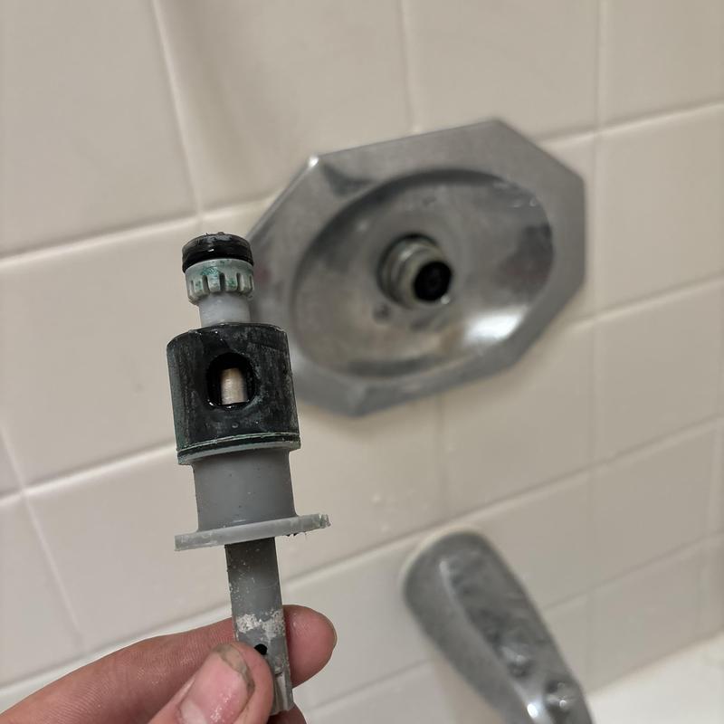 Pfister shower cartridge held in hand near valve trim