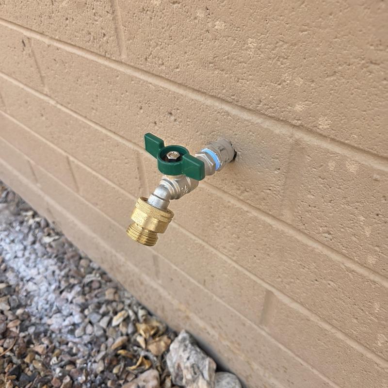 Stainless steel quarter turn hose bib on brick wall