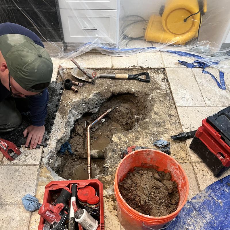 Copper water pipe exposed in slab with tools nearby