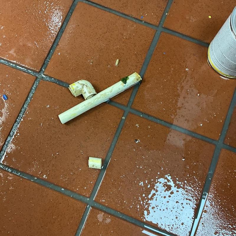 Half-inch kitchen sink pipe and coupling on tiled floor Half-inch kitchen sink pipe and coupling on tiled floor