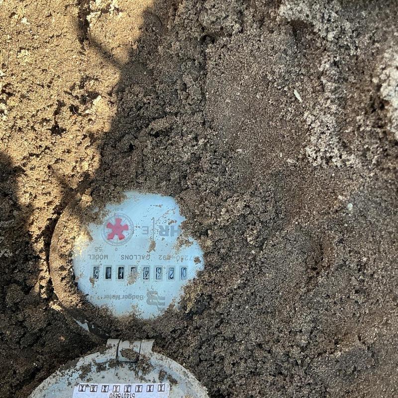 Water meter partially covered by soil and dirt outdoors Water meter partially covered by soil and dirt outdoors