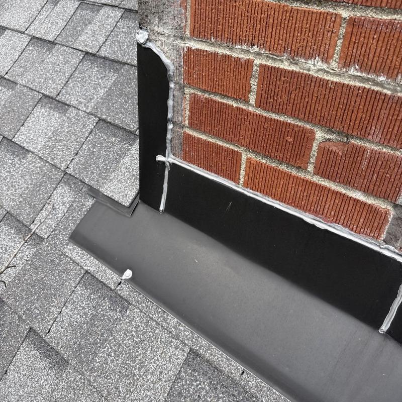 Chimney metal flashing with sealant on roof edge Chimney metal flashing with sealant on roof edge