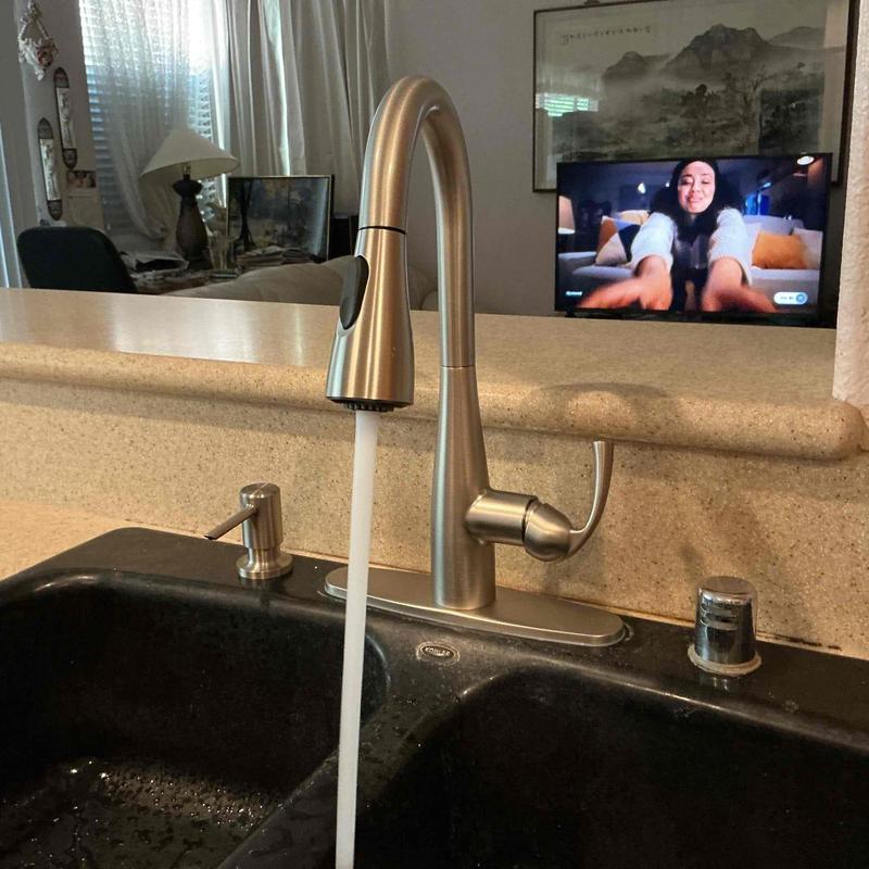 Kitchen faucet with running water in black sink