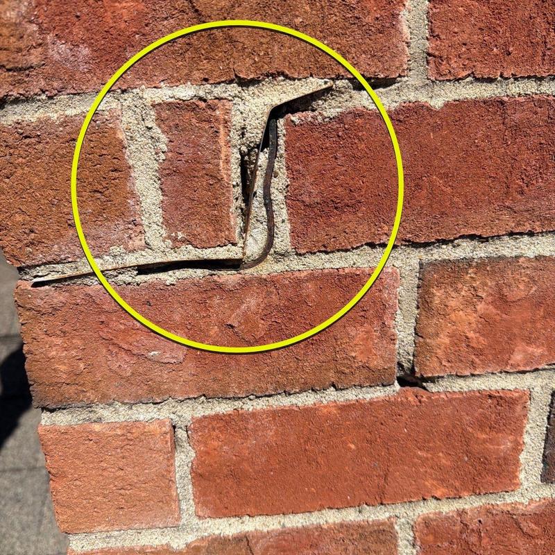 Brick wall mortar crack with gap highlighted in yellow circle