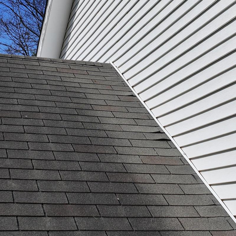Asphalt shingles with damaged areas near siding joint