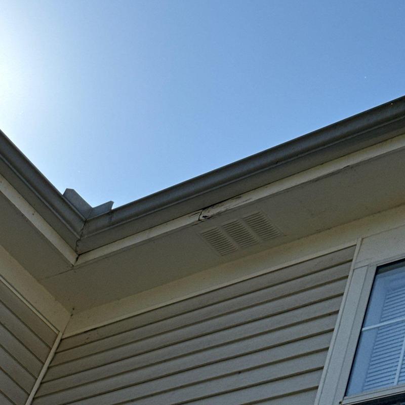 Gutter and soffit corner with minor damage under sunlight