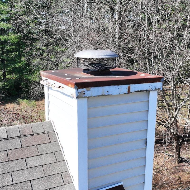 Chimney cap and flashing with rust and wear on roof
