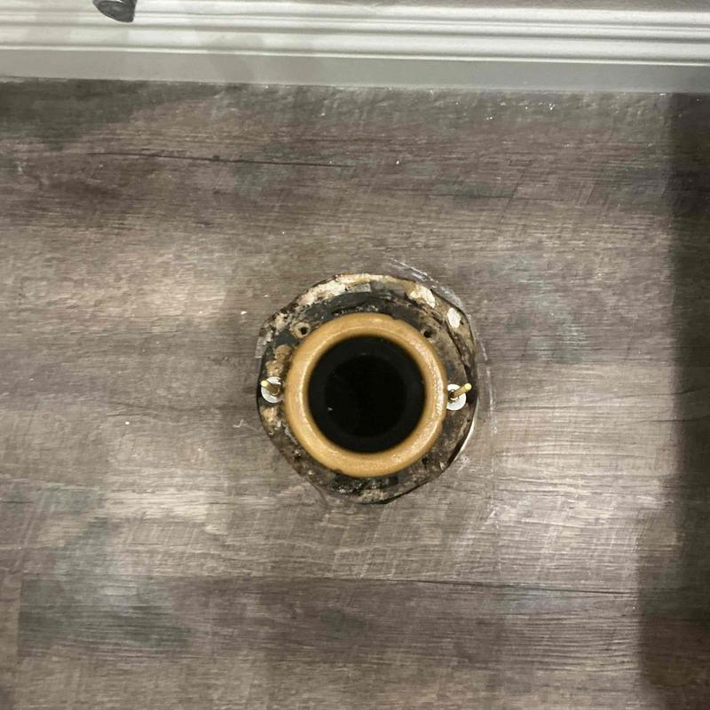 Toilet flange with wax ring removed on bathroom floor