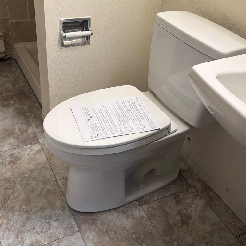 Toilet with installation instructions on lid in bathroom Toilet with installation instructions on lid in bathroom