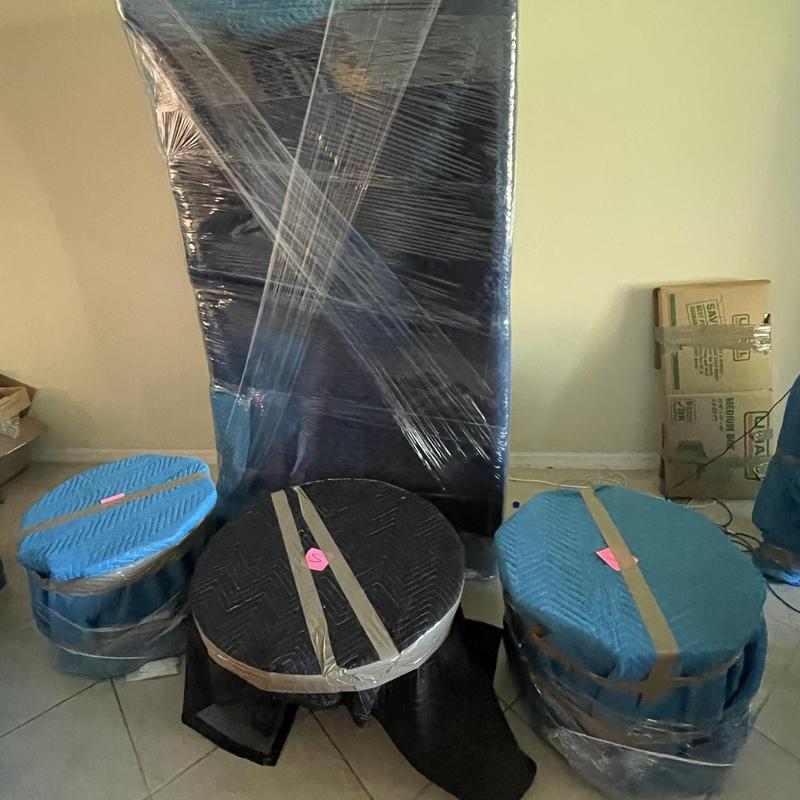 Furniture wrapped in protective moving blankets and plastic wrap