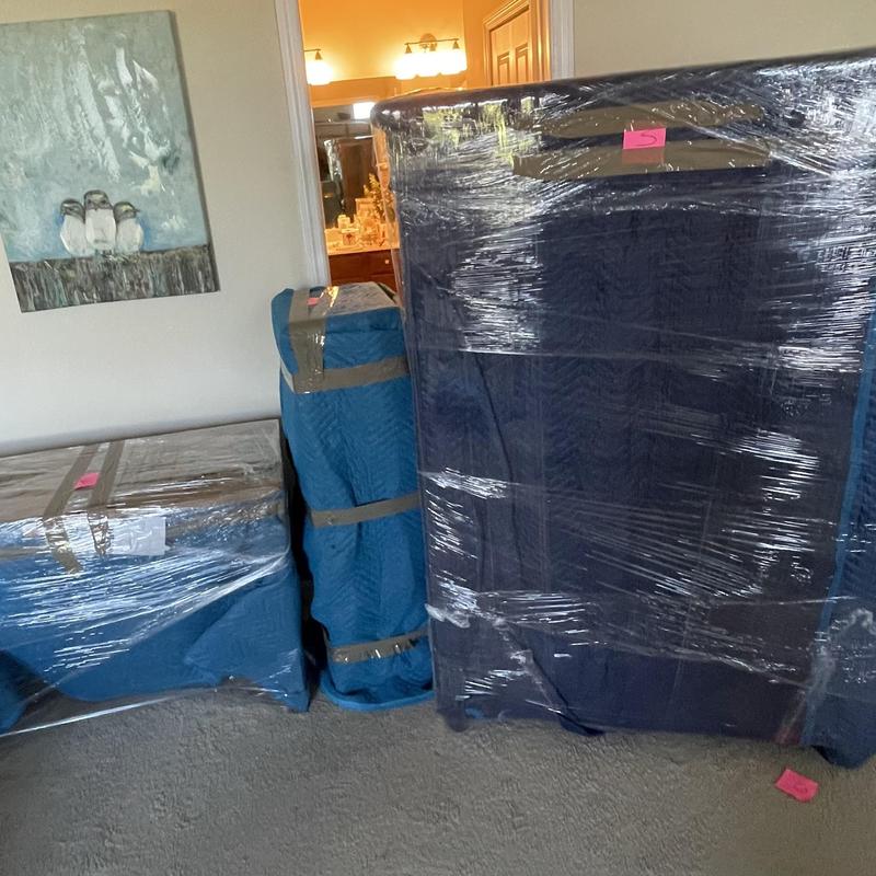 Furniture wrapped in moving blankets and plastic wrap