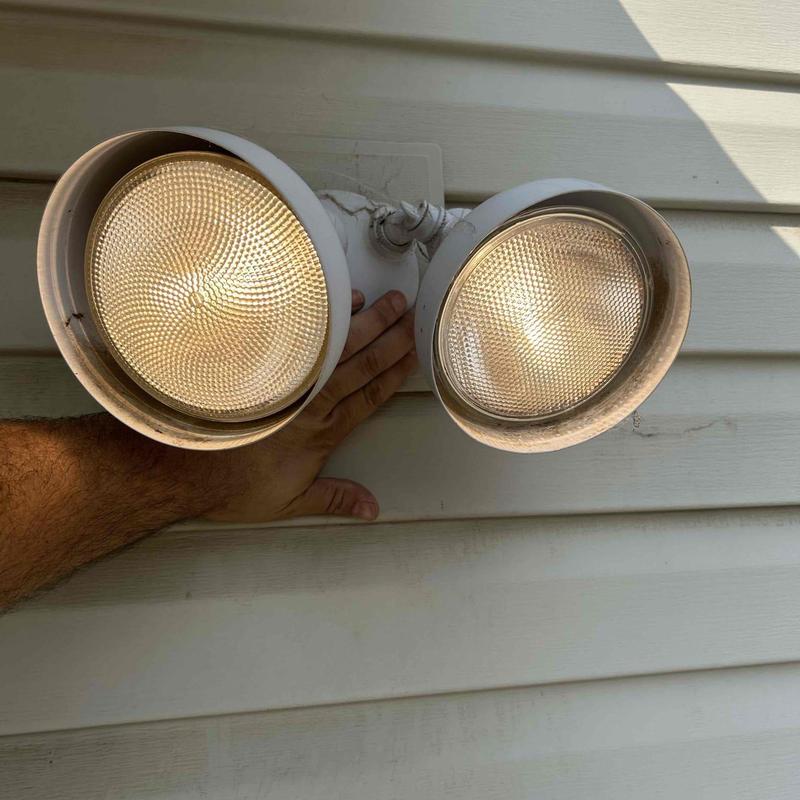 Outdoor floodlight fixture with hand for testing bulb