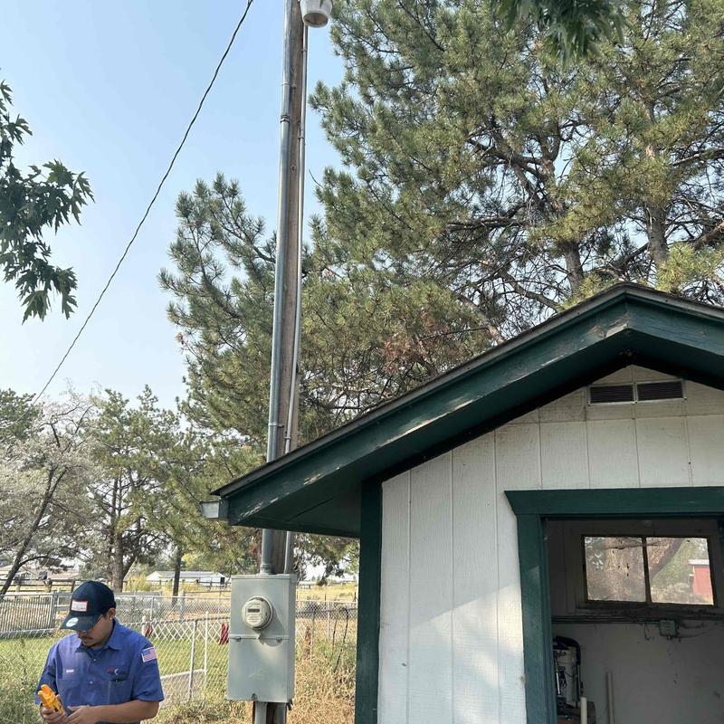 Electric meter installation beside small shed outdoors