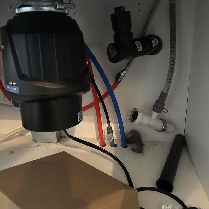 Garbage disposal and plumbing pipes inside cabinet panel