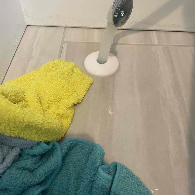 Toilet supply line leak with towels on tile floor