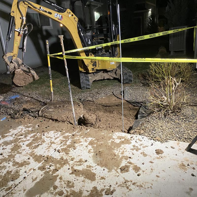 Water meter vault excavation with backhoe at night
