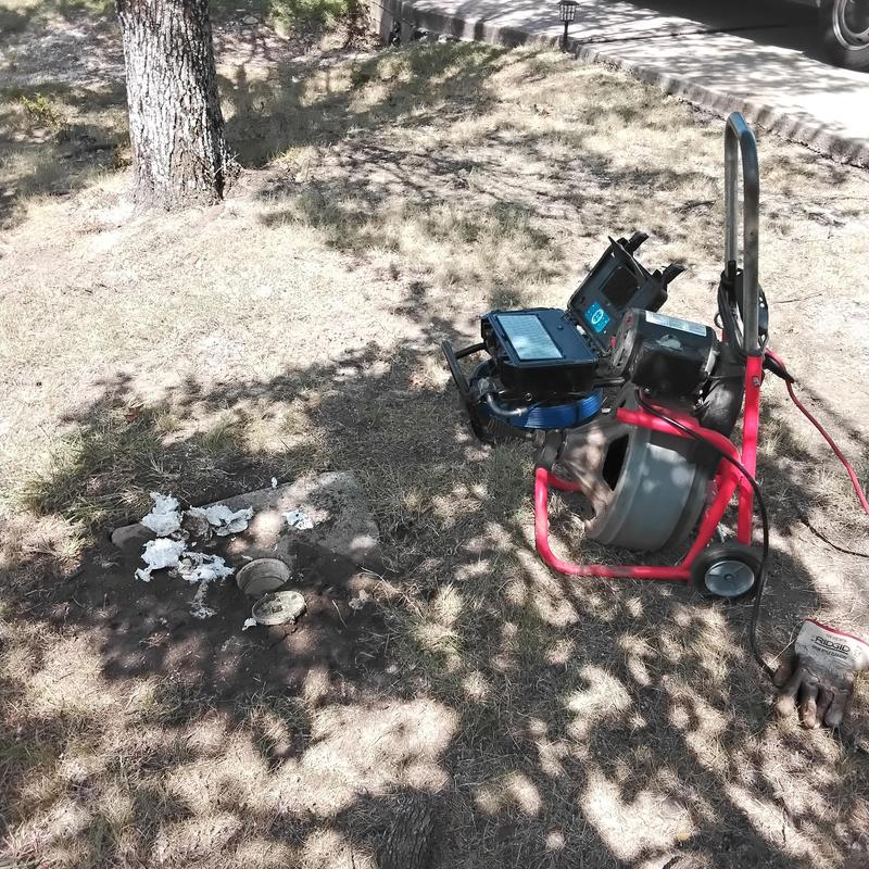 Sewer line cleanout with cable machine in yard