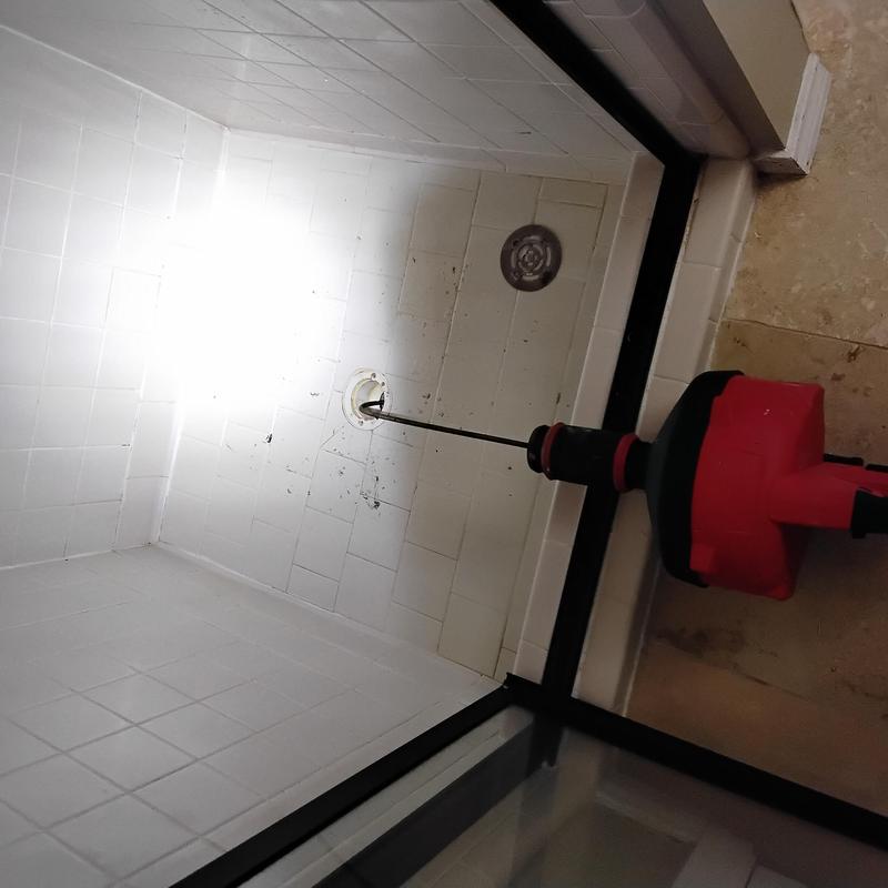 Shower drain with plumbing cable clearing paper clog