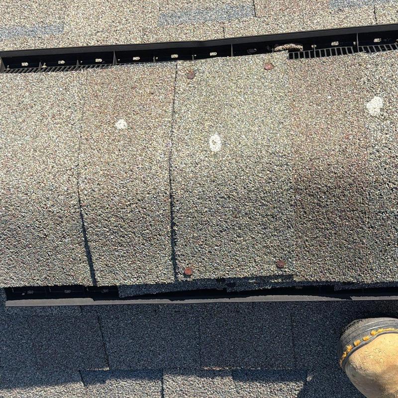 Roof shingles with visible hail damage spots and nails
