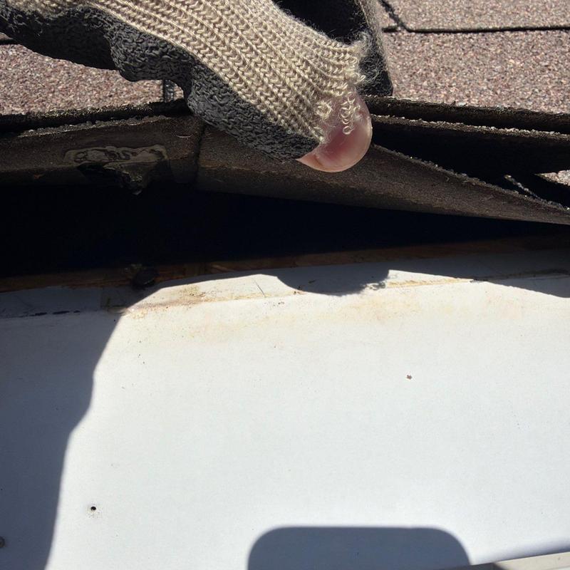 Roof shingles lifted showing damage underlayment layer