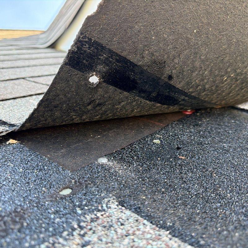 Roofing underlayment lifted showing hail damage on shingles