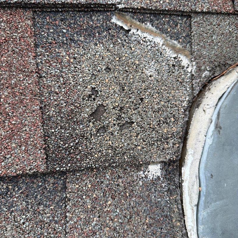 Roof shingles with hail damage near flashing sealant