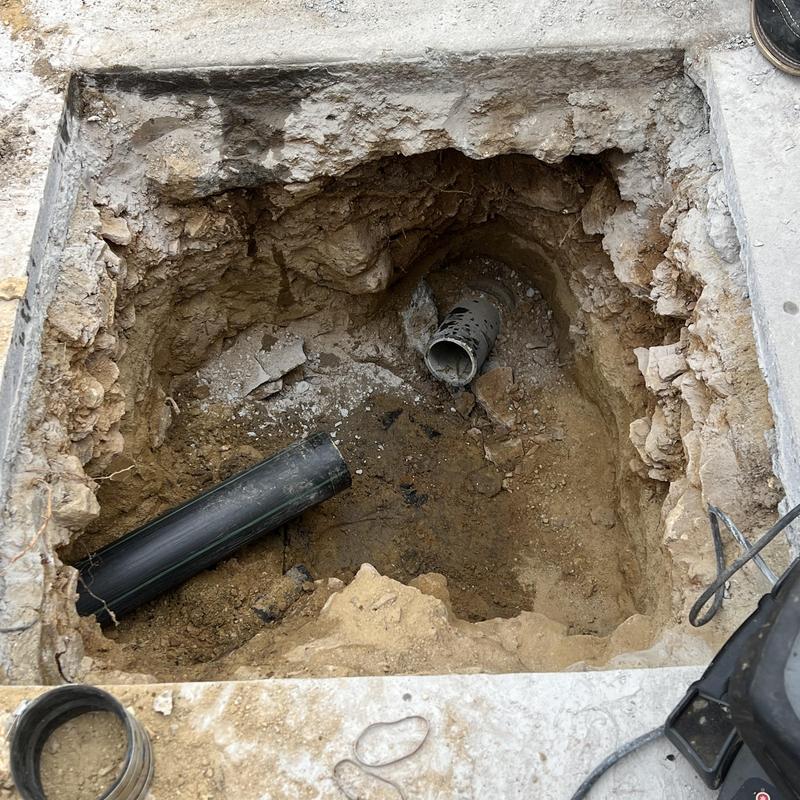 Lateral sewer line excavation with exposed pipe ends