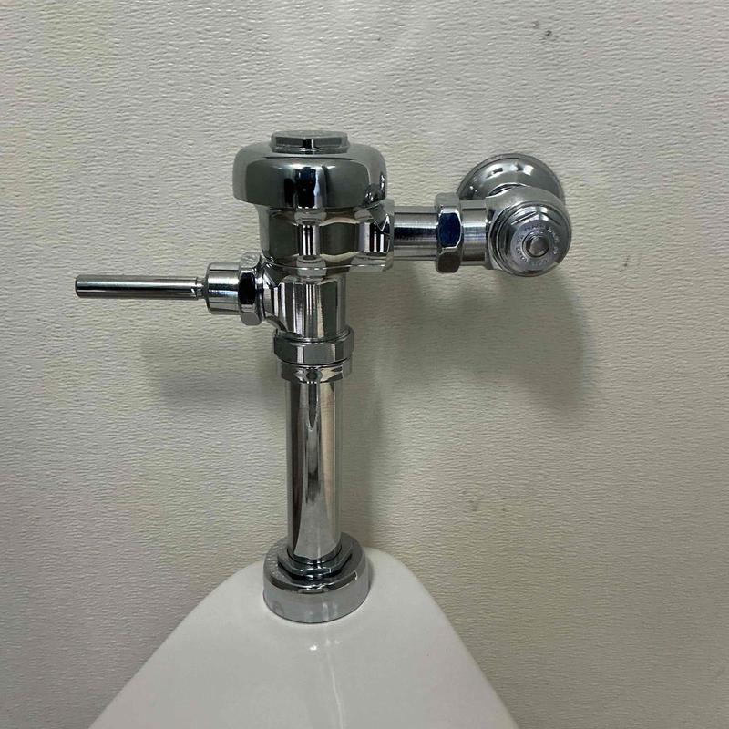Sloan flush valve on urinal installation in bathroom