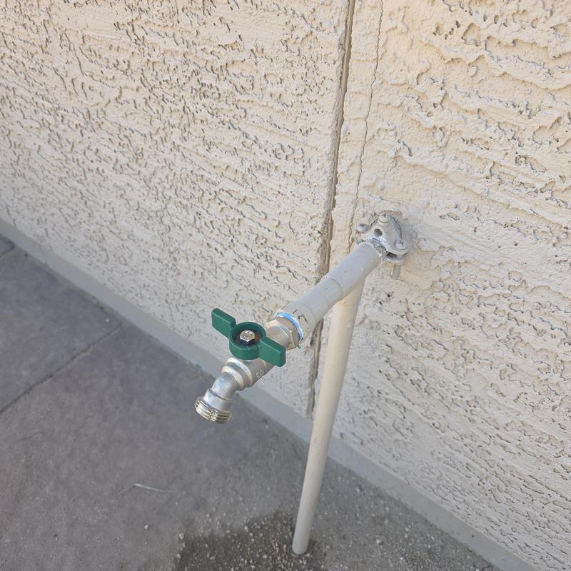 Stainless steel outdoor hose bib on stucco wall