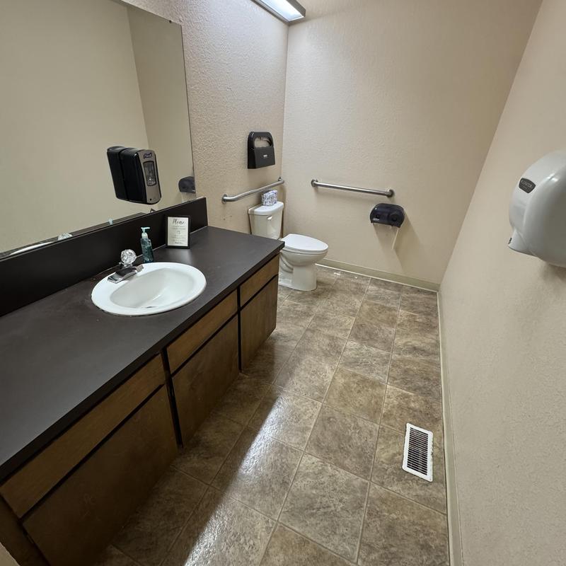Commercial toilet and sink in restroom with handrails Commercial toilet and sink in restroom with handrails