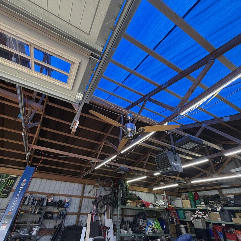 Barn roof framing with blue tarp cover inside garage Barn roof framing with blue tarp cover inside garage