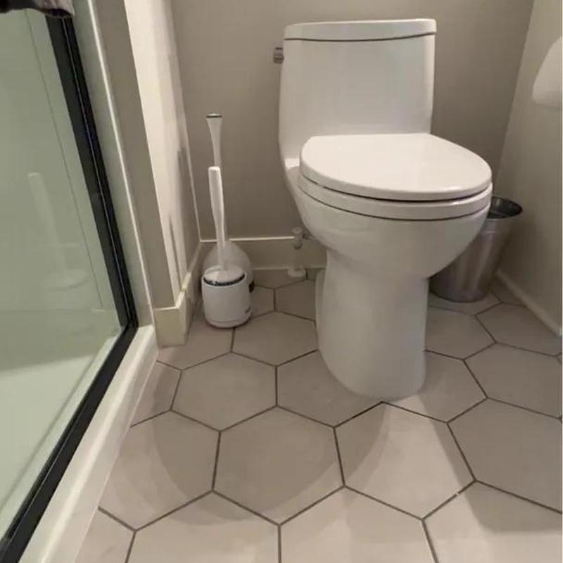 Toilet with white hex tile floor in bathroom corner