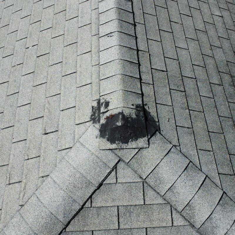 Shingle roof ridge with patch and granule loss Shingle roof ridge with patch and granule loss