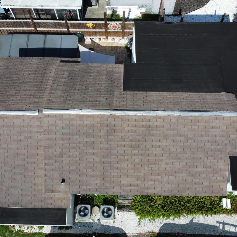 Shingle roof with flat roof section and HVAC units above house