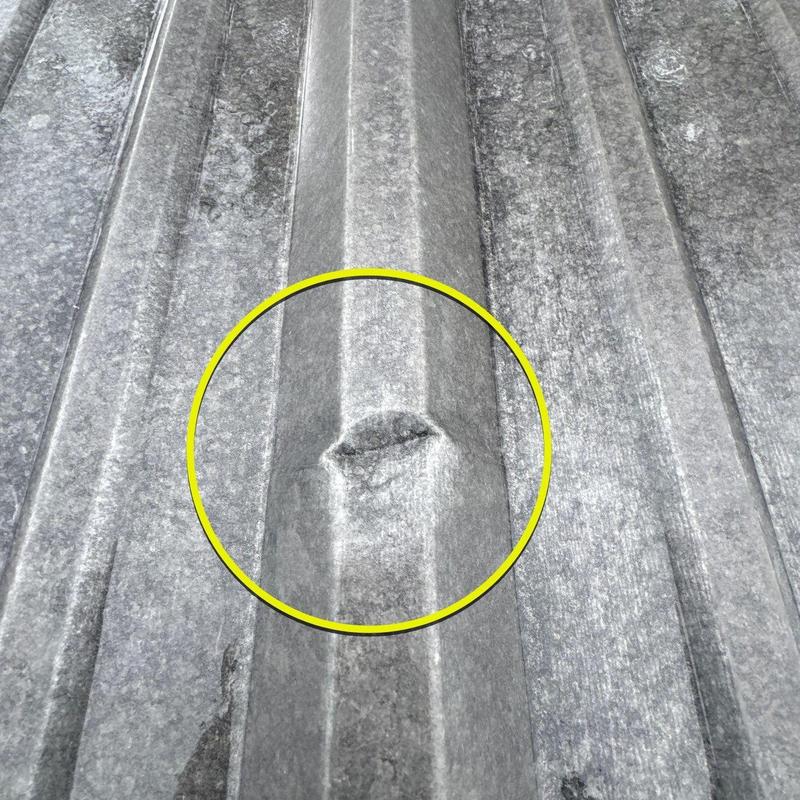 Metal roof panel dent with hail damage highlighted