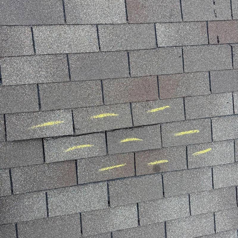 Asphalt shingle roof with hail damage marked in yellow