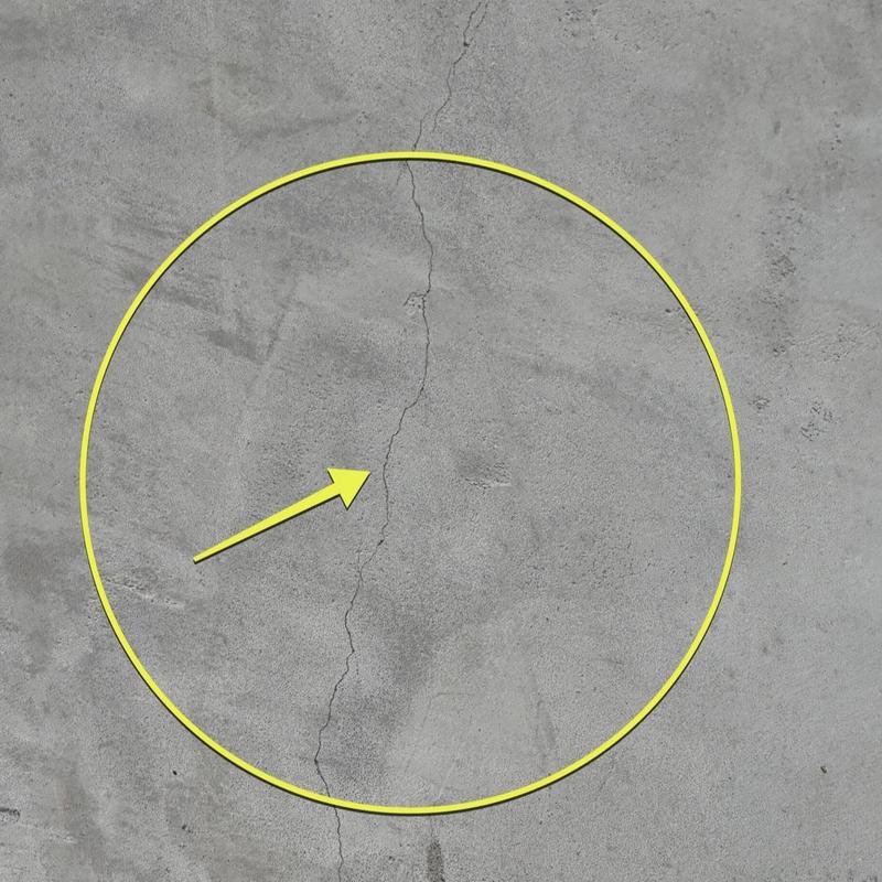Stucco hairline crack with yellow marking and arrow