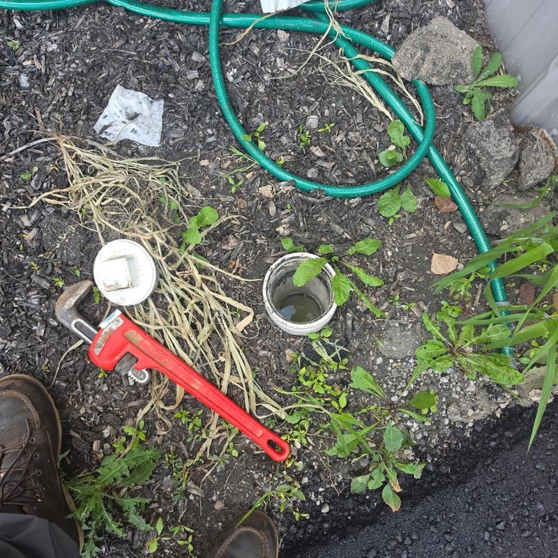 Main sewer cleanout with plumbing wrench and hose
