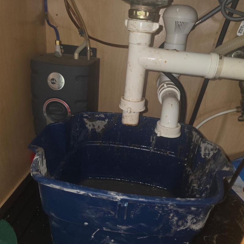 P-Trap plumbing with bucket catching debris under sink
