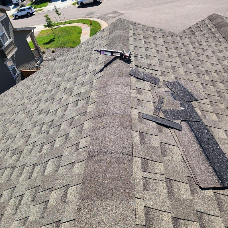 Roof ridge with shingles and sealant gun during repair Roof ridge with shingles and sealant gun during repair