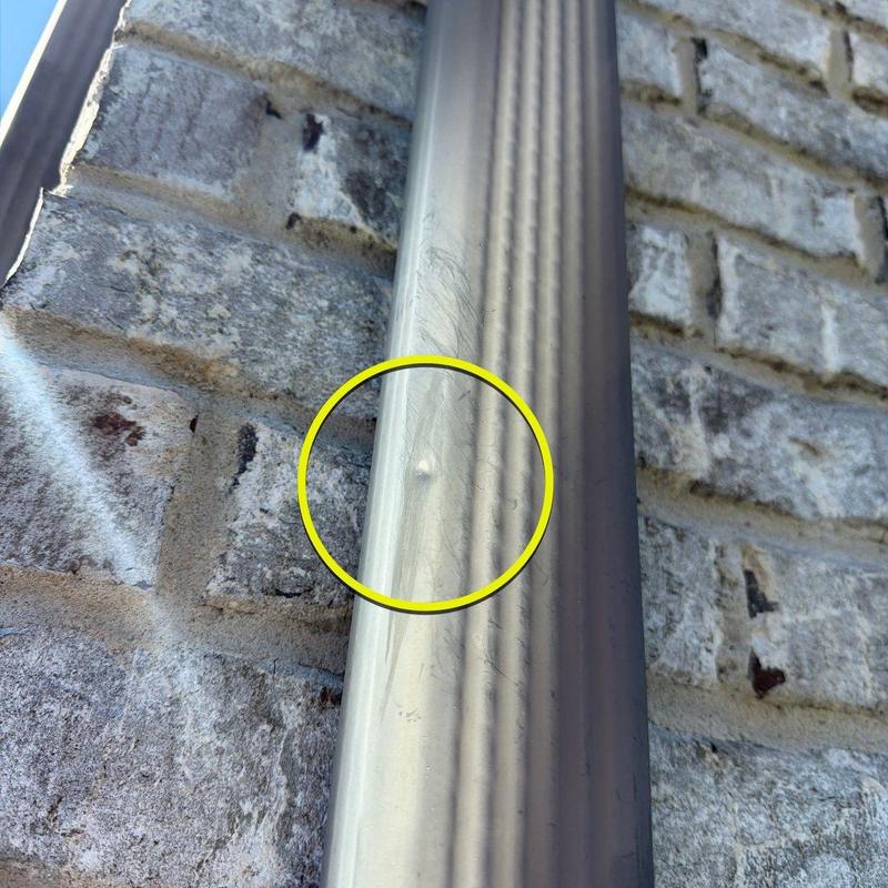 Metal downspout with dent from hail damage