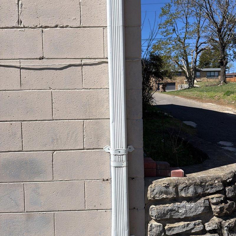 Downspout and wall mounting bracket on beige building