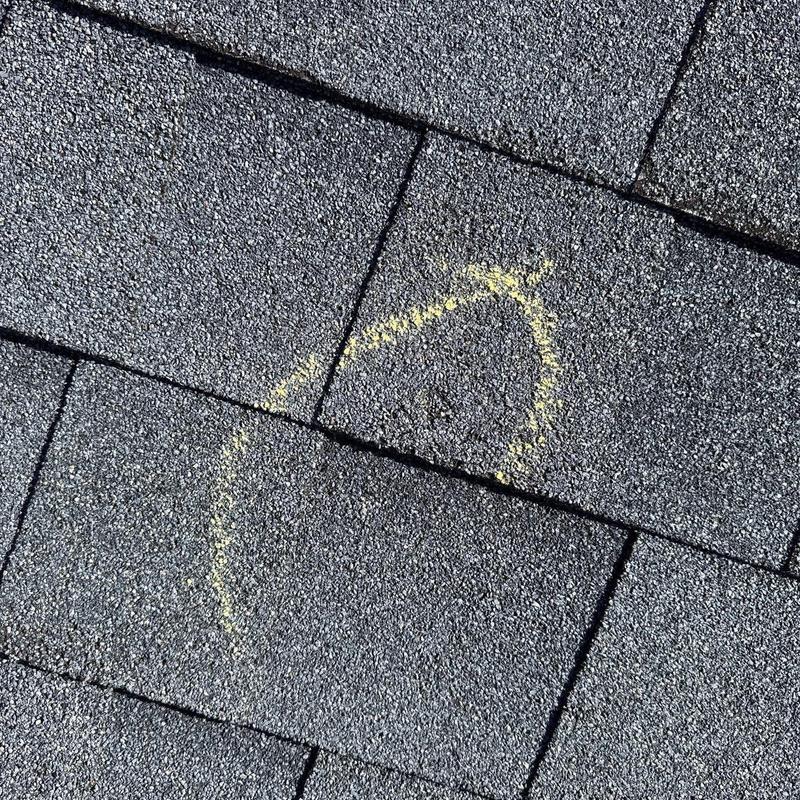 Asphalt shingle with hail damage marked in yellow