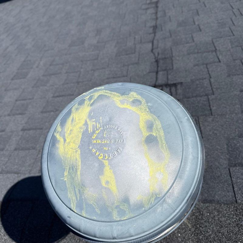 Metal roof vent cap with yellow chalk markings on shingles