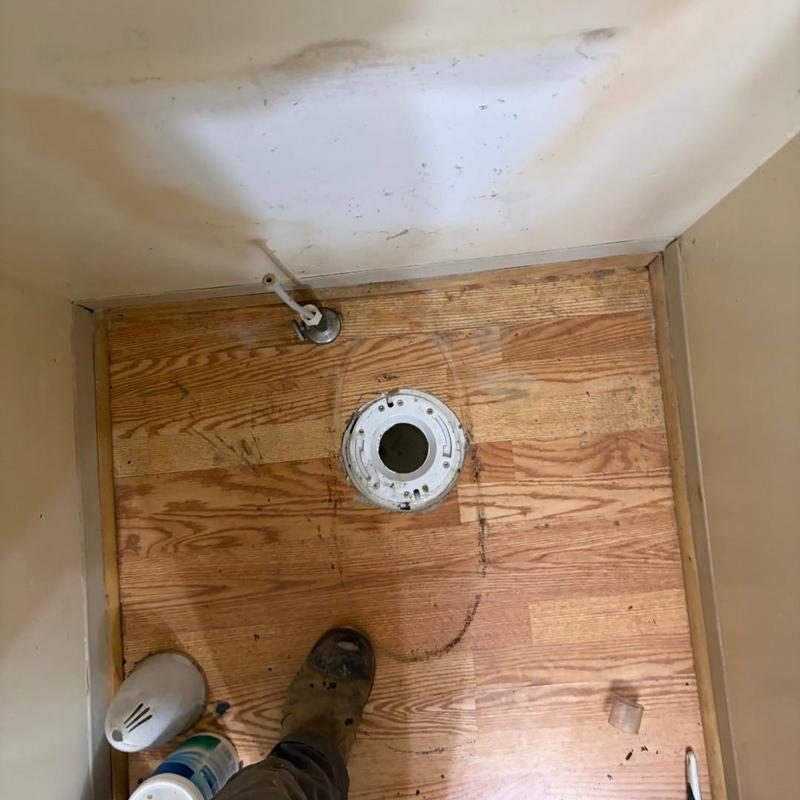 Toilet flange with pipe and wooden floor in bathroom
