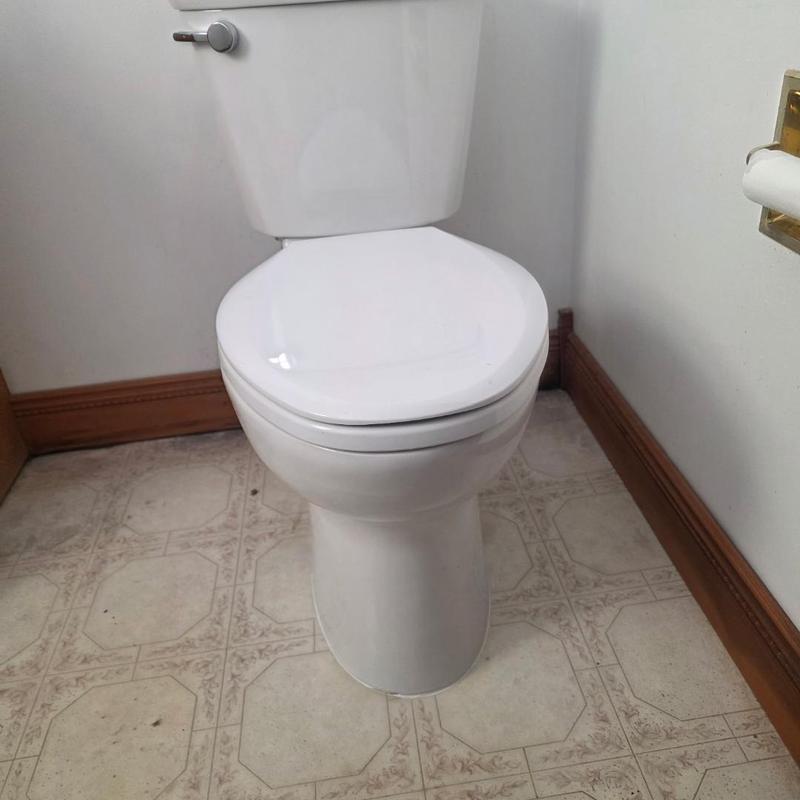 Toilet installation in bathroom corner with tile floor