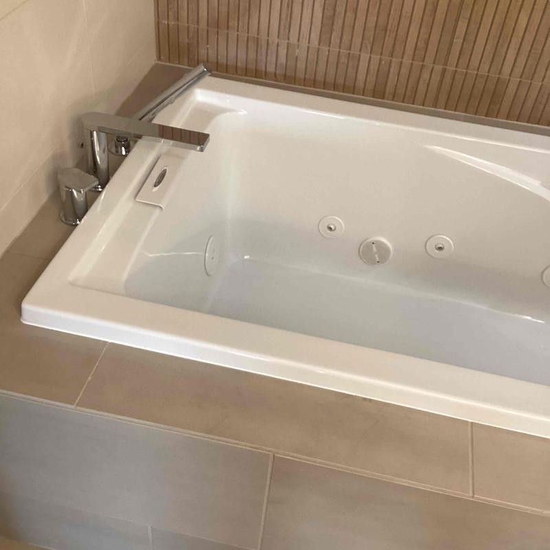 Bathtub with faucet and leak repair in tiled bathroom Bathtub with faucet and leak repair in tiled bathroom