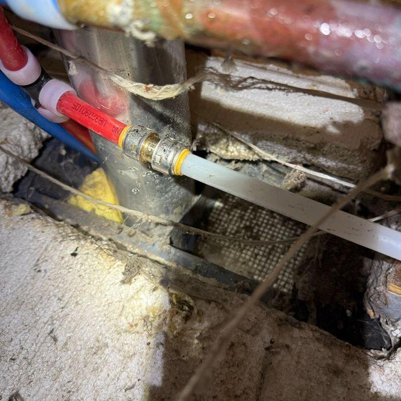 PEX plumbing pipes and metal connector fitting underneath floor