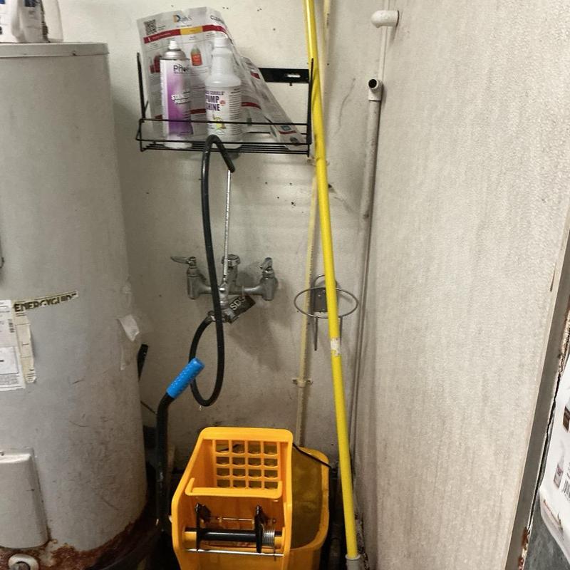 Water heater and mop sink area with cleaning supplies Water heater and mop sink area with cleaning supplies
